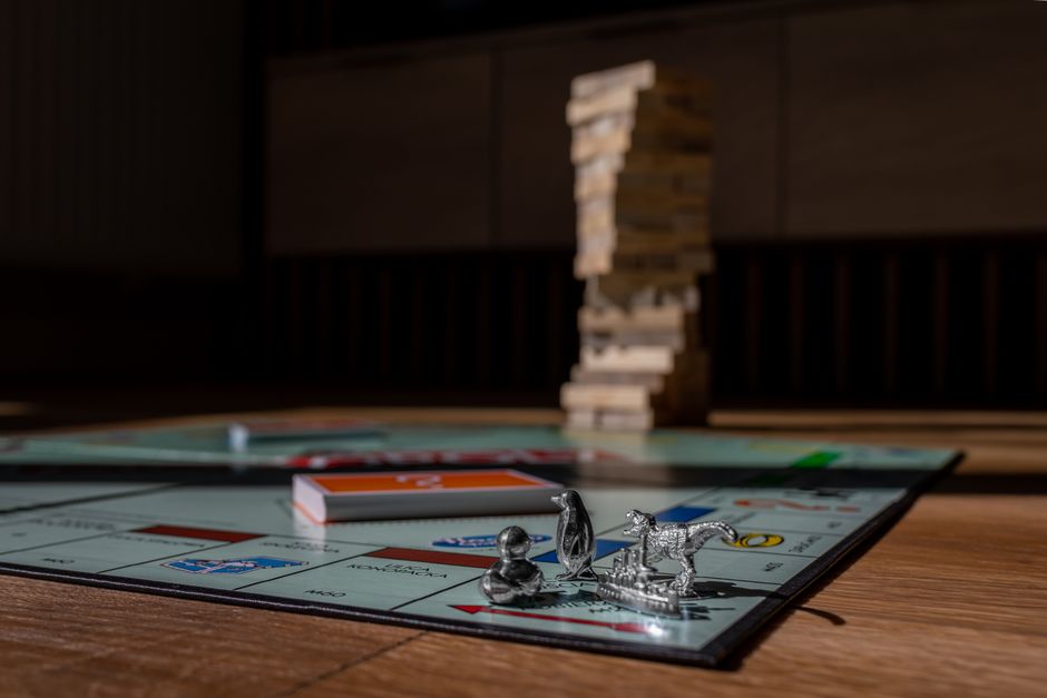 Close-up view of Monopoly board game with metal tokens and stacked Jenga blocks on a table.
