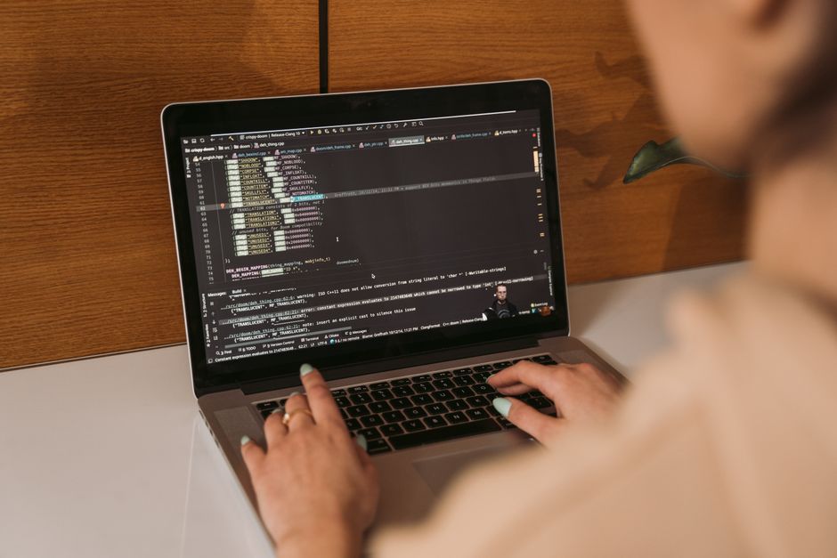 Close-up of a woman coding using a laptop in an office environment, showcasing modern technology.