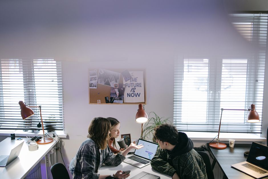 A group of people discussing ideas around laptops in a bright, modern office space.