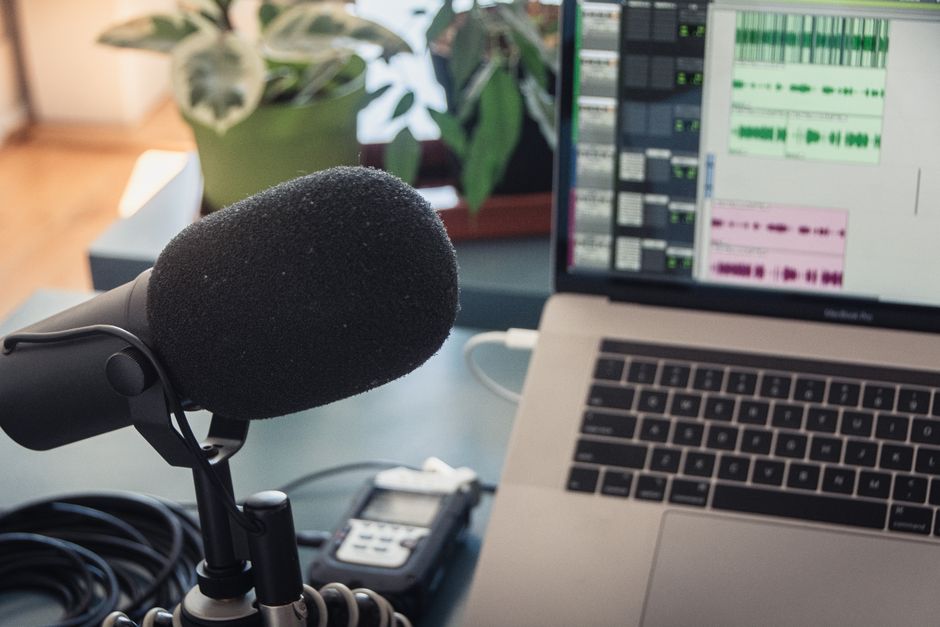 A podcast recording setup with a laptop, microphone, and audio equipment indoors.