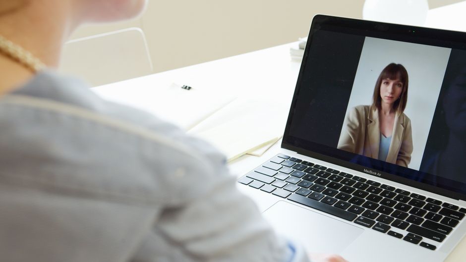 Close-up of woman on a video call using a laptop in a modern workspace.