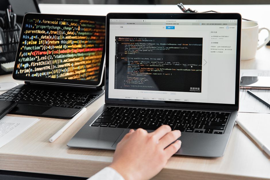 A developer writing code on a laptop, displaying programming scripts in an office environment.